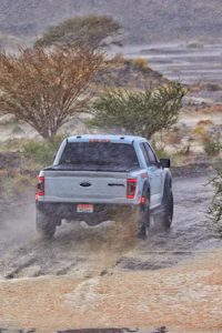 a white truck driving through a muddy area