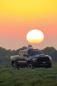 a person is sitting on top of a truck at sunset