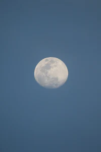 the moon is seen through a clear blue sky